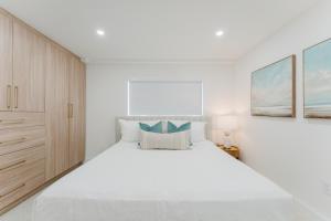 a white bedroom with a large bed and cabinets at The Courtyard - Poolside Suite in Boca in Boca Raton +26 photos