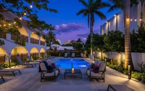 a resort pool with chairs and a table with a candle at The Courtyard - Poolside Suite in Boca in Boca Raton