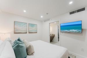 a white bedroom with a bed and a tv on the wall at The Courtyard - Poolside Suite in Boca in Boca Raton