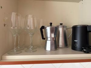a row of wine glasses and a coffee maker on a shelf at tud dret in Santa Maria