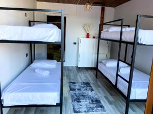 two bunk beds in a room with white sheets at Hub 1001 Berat Hostel in Berat
