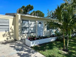 a white house with a palm tree in front of it at Conch Shell Cabana in Vero Beach