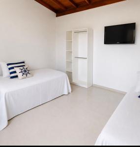 a white room with two beds and a tv at Ocean Residence - Aptos Pé na Areia Ponta do Papagaio in Palhoça