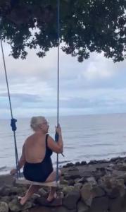 a woman sitting on a swing by the water at Borbon's Treehouse By the Sea in Mambajao