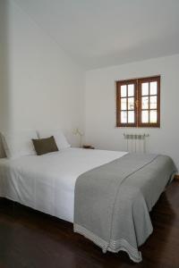 a white bed in a white bedroom with a window at Casa da Pedrada in Ponte da Barca