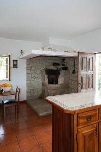 a kitchen with a stone fireplace with a table and a counter at Casa da Pedrada in Ponte da Barca