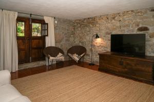 a living room with two chairs and a flat screen tv at Casa da Pedrada in Ponte da Barca