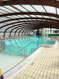 a large swimming pool with blue water in a building at Mobile home in Litteau