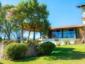 a house with trees and bushes in front of it at Villa da Vila Montanhas in Monte Verde