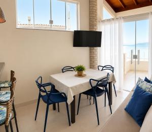 a dining room with a table and blue chairs at Ocean Residence - Aptos Pé na Areia Ponta do Papagaio in Palhoça
