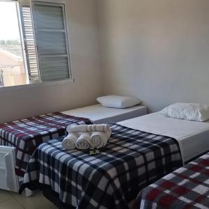 a room with two beds with towels on a table at Hotel Cardoso Trindade in Juruaia