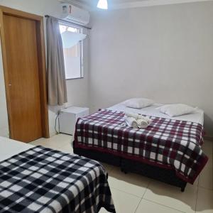 a bedroom with two beds with a checkered blanket at Hotel Cardoso Trindade in Juruaia