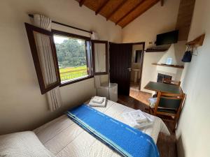 a small bedroom with a bed and a window at Villa da Vila Montanhas in Monte Verde