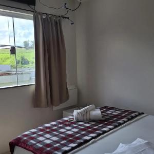 a room with a bed with a checkered blanket on it at Hotel Cardoso Trindade in Juruaia