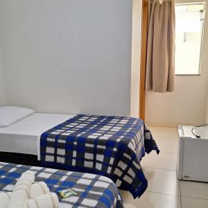 a bedroom with two beds with blue and white sheets at Hotel Cardoso Trindade in Juruaia