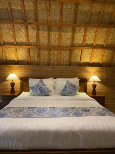 a bedroom with a white bed with two lamps at Griya Garden Penida in Nusa Penida