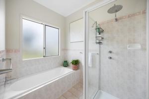 a bathroom with a tub and a shower with a window at Salt & Stay - Laid-Back Comfort by the Beach in Encounter Bay +15 photos