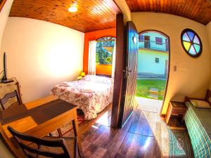 a bedroom with a bed and a table in a room at Villa da Vila Montanhas in Monte Verde