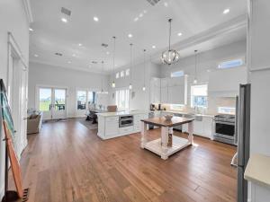a kitchen with white cabinets and a wooden table at Luxury Beachfront Ocean Views Pool Access Sleeps15 in Bolivar Peninsula