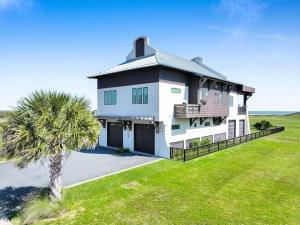 a white house with a palm tree in front of it at Luxury Beachfront Ocean Views Pool Access Sleeps15 in Bolivar Peninsula
