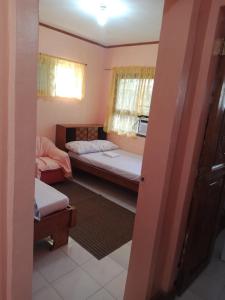 a small room with two beds and a window at Ancestral BATO in Bato