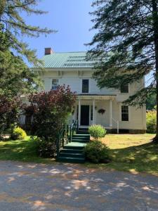 a white house with stairs leading to the front door at Sweet Stowe Apartment in Stowe