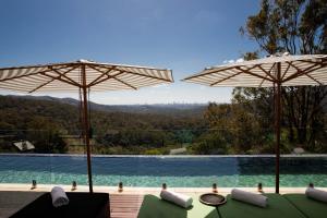 a swimming pool with two umbrellas next to a swimming pool at On Eagle Wings Mountain Retreat & Spa in Neranwood +33 photos
