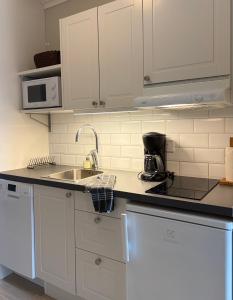 a kitchen with white cabinets and a sink at Närebo Gårdshotell in Lidköping +8 photos