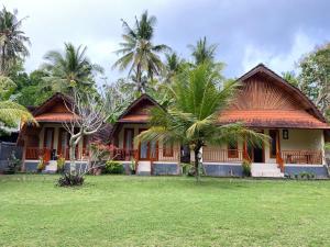 a house with palm trees in front of it at Griya Garden Penida in Nusa Penida