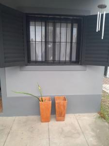 two vases sitting next to a wall with a window at Amaicha Luján in Luján
