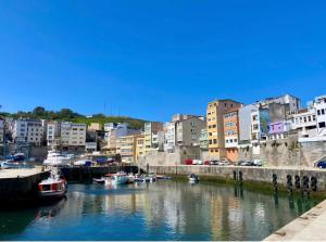 a river with boats in a city with buildings at Costa Canido I in Malpica