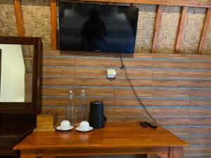 a wooden table with a television on a wall at Griya Garden Penida in Nusa Penida