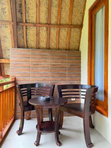 a wooden table and two chairs and a wooden wall at Griya Garden Penida in Nusa Penida