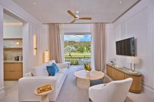 a living room with a white couch and a tv at Calabash Hotel in Saint Georgeʼs