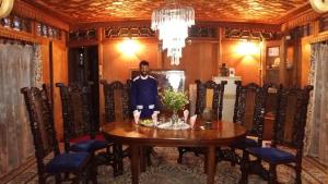 a man standing at a table in a dining room at Jacqueline houseboat in Srinagar