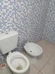 a bathroom with a toilet and a blue and white tiled wall at Sierras Cosquin in Cosquín