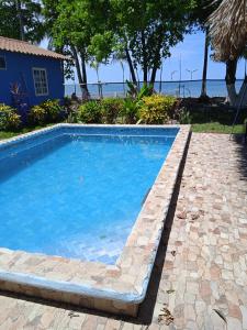 a swimming pool with a stone walkway next to the ocean at Sunrise Inn in Puerto Armuelles +13 photos