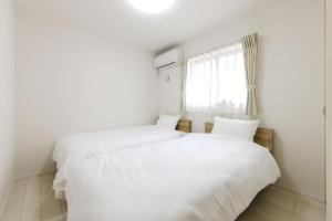 two white beds in a room with a window at AsobiStay児玉藤 in Nagoya