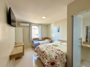 a bedroom with a bed and a television in it at Hotel C Diamantina in Vitória da Conquista