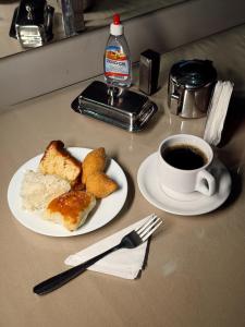 a table with a plate of food and a cup of coffee at Hotel C Diamantina in Vitória da Conquista