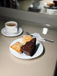 a plate with chocolate cake and biscuits and a cup of coffee at Hotel C Diamantina in Vitória da Conquista +15 photos