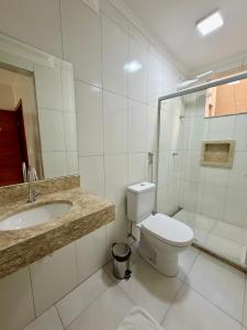 a white bathroom with a toilet and a sink at Hotel C Diamantina in Vitória da Conquista