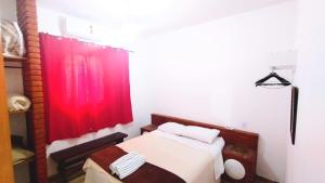 a bedroom with a bed with a red curtain at Recanto das Termas, Chalés in Termas do Ibirá