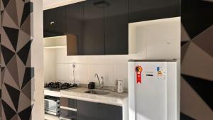 a kitchen with a white refrigerator and a stove at Aprt com ar varada conjugada,piscina in Aracaju