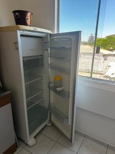 an empty refrigerator with its door open in a kitchen at Loft Pedra Branca - Unisul in Palhoça