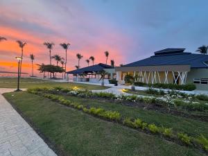 a building with palm trees and a sunset in the background at Oceanfront Paradise Beach Resort Escape in San Felipe de Puerto Plata