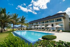 a resort with a swimming pool with chairs and umbrellas at Oceanfront Paradise Beach Resort Escape in San Felipe de Puerto Plata