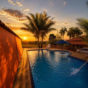 a swimming pool with a sunset in the background at Pousada Serra Dourada Mossâmedes in Mossâmedes