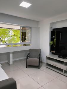 a living room with a chair and a flat screen tv at Prédio Solar do Atlântico, apt 204 - Apartamento lateral em Tambaú in João Pessoa
