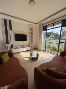a living room with two chairs and a flat screen tv at Pearl Escape in Entebbe